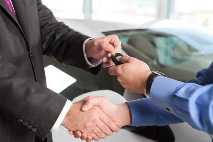 Car salesperson delivering a key to a customer